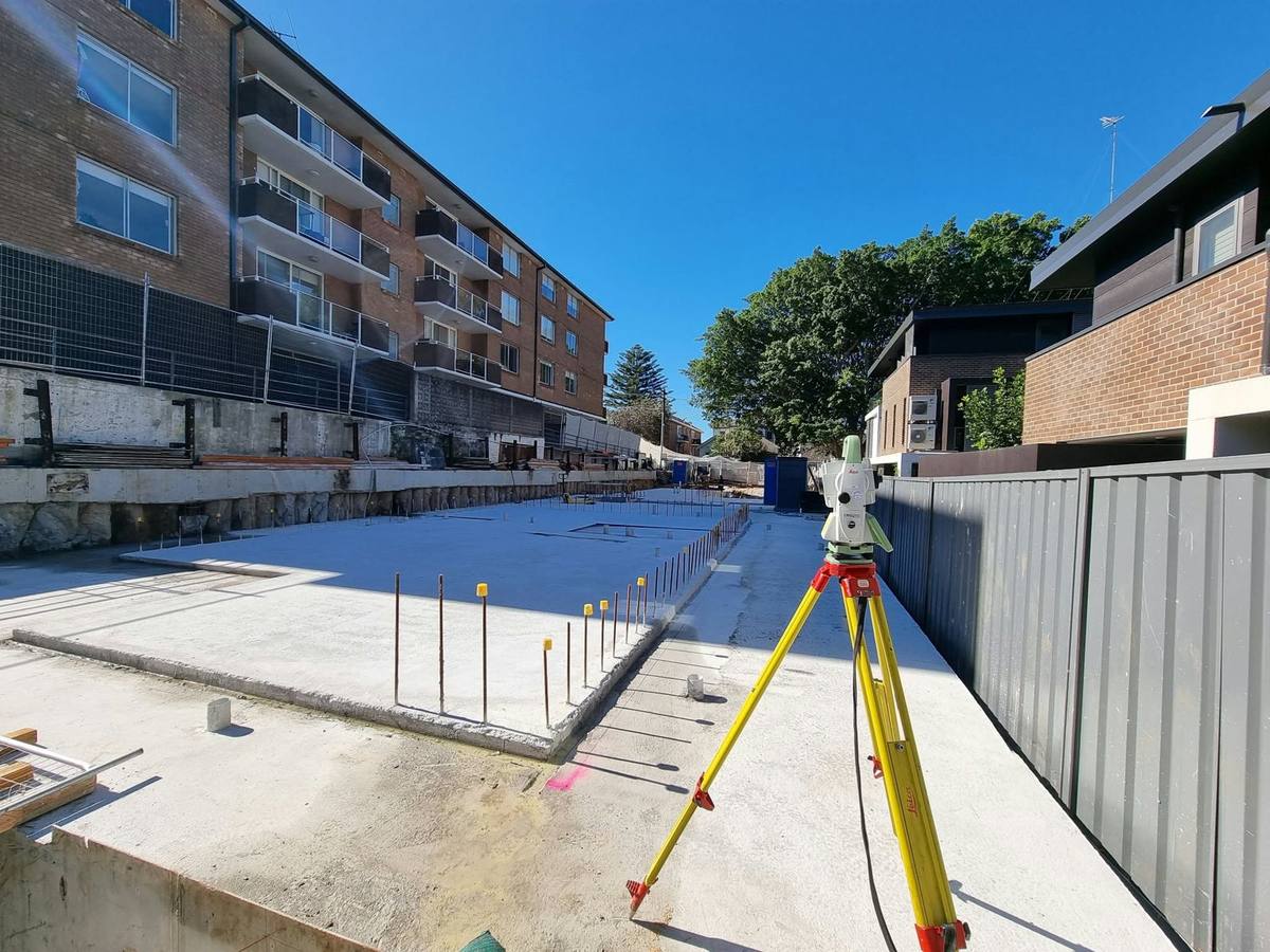 Total station beside a new concrete slab with starter bars